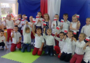 Grupa dzieci pozuje do zdjęcia prezentując jednocześnie wykonane samodzielnie flagi na patyczkach.
